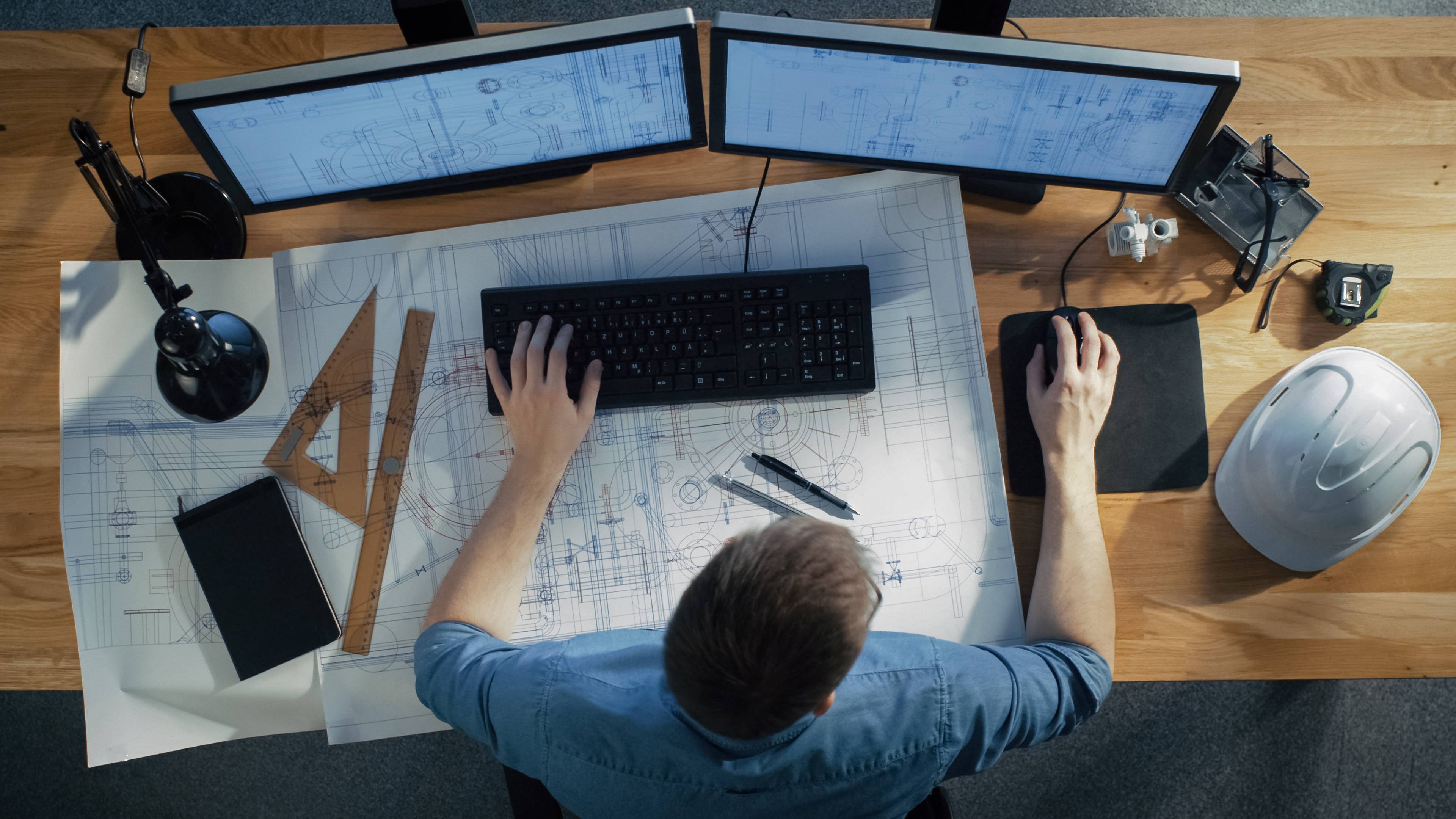 Person working at a desk with drawings and a computer