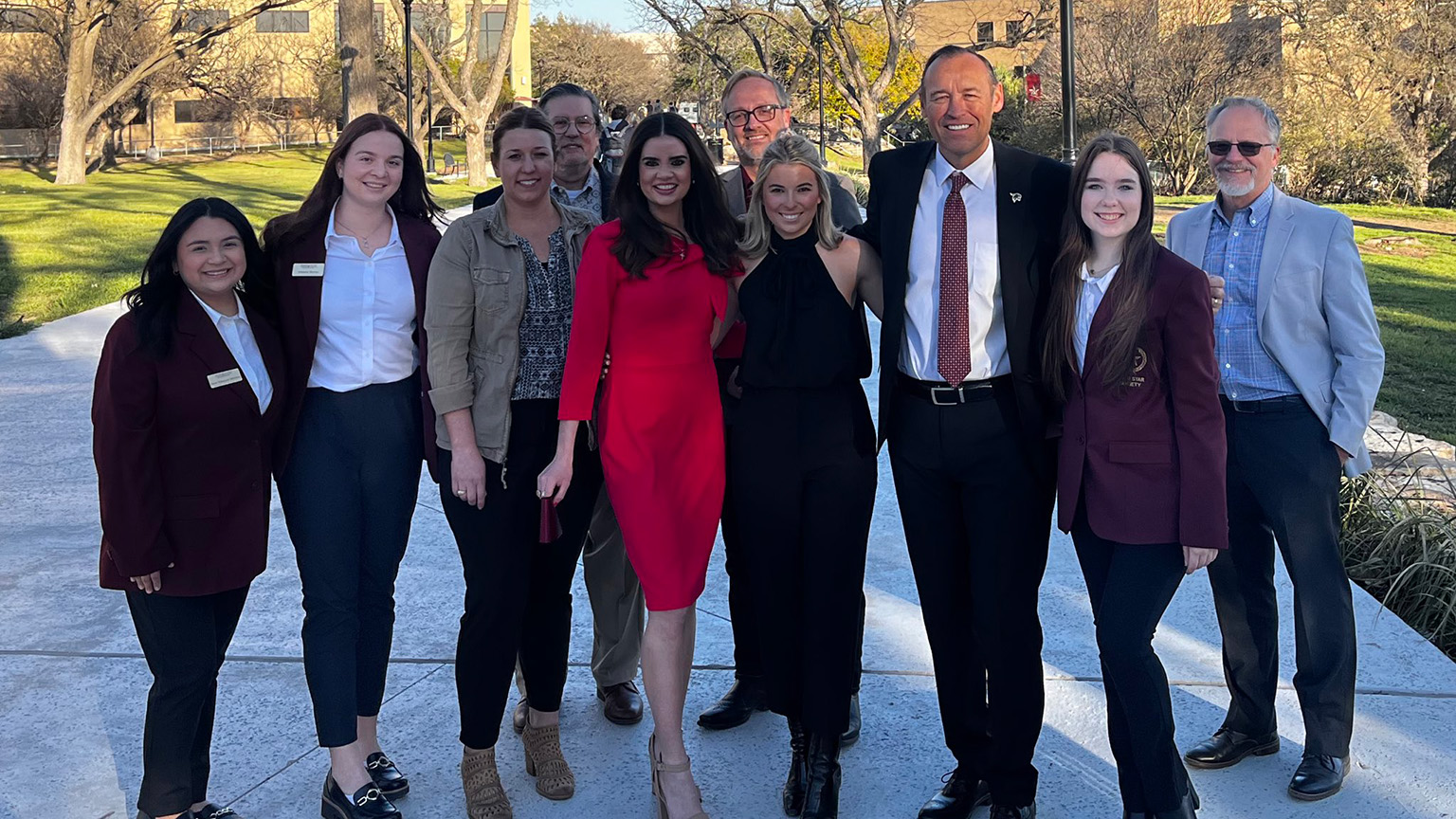 A group of staff members and students pose for a photo with President Damphousse.