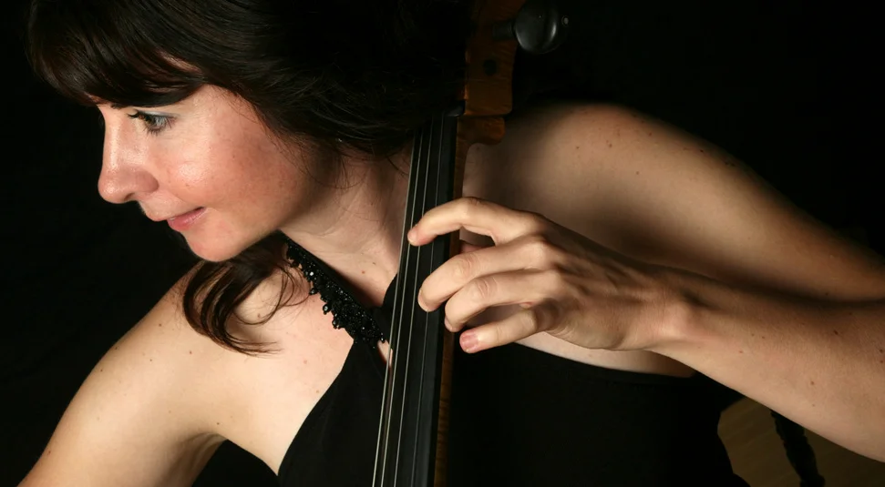 A woman wearing a black gown playing the cello.