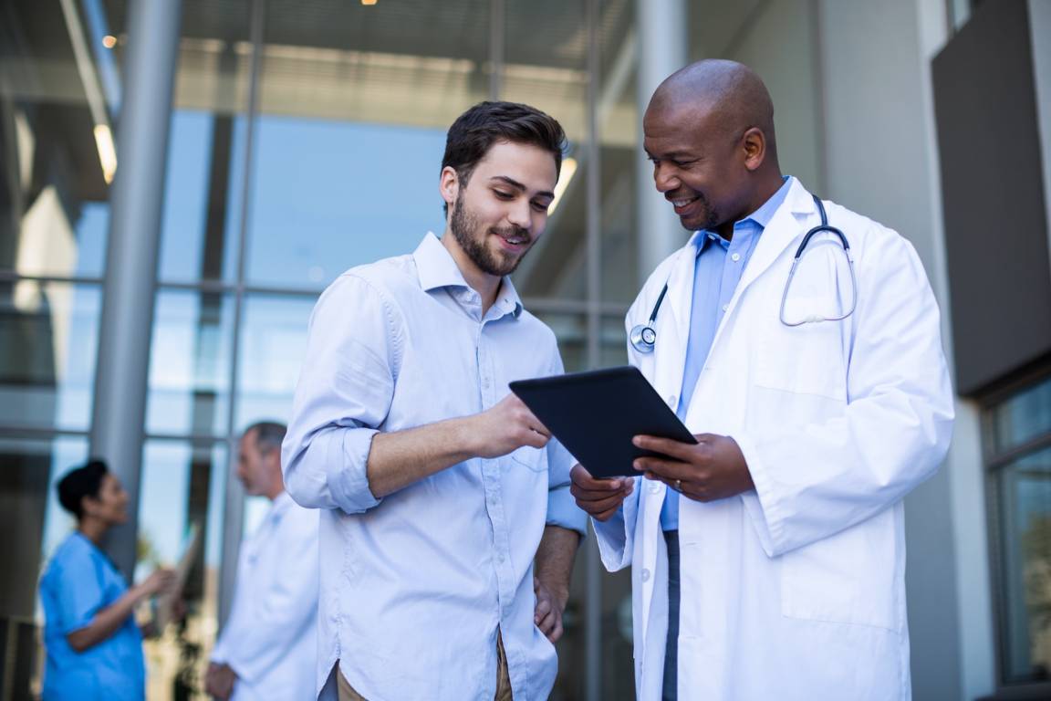 Doctor in white coat showing patient a tablet.