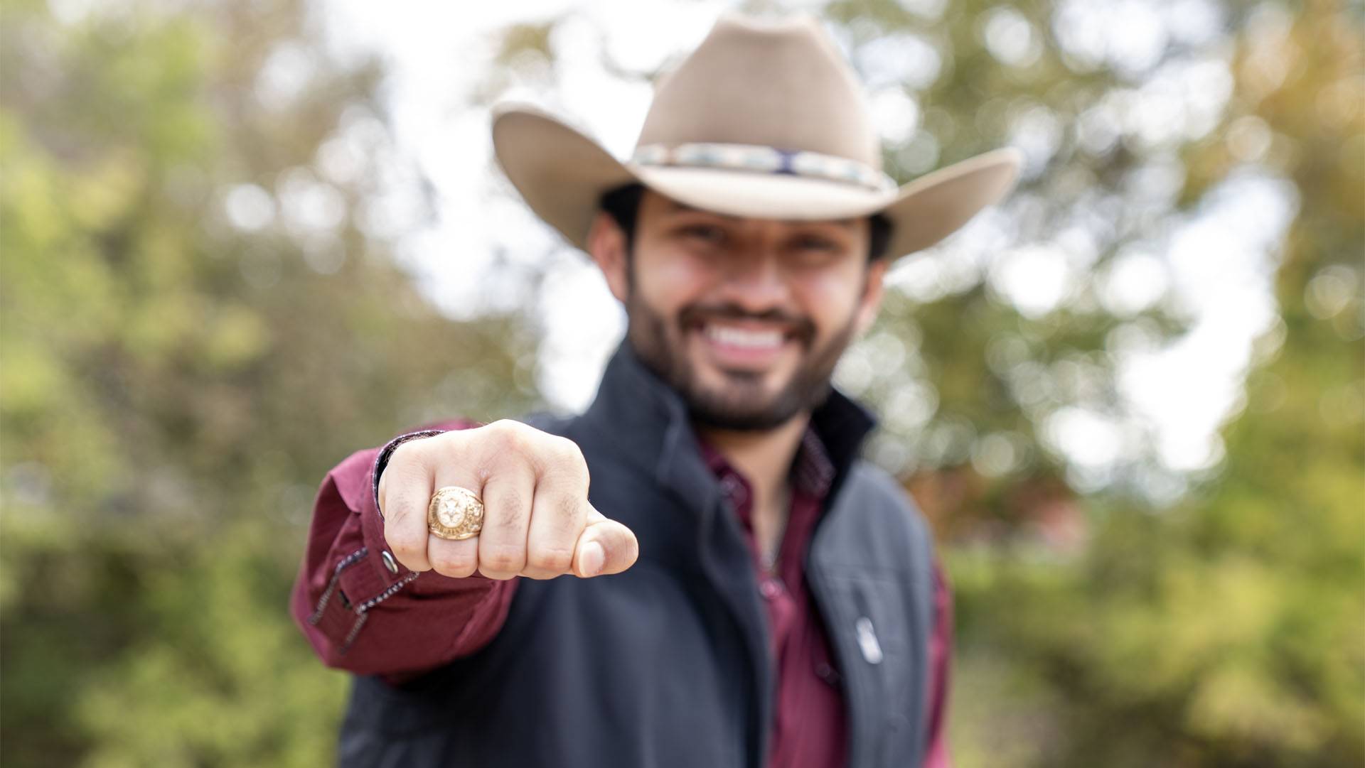 photo of man smiling and showing off Texas State ring.