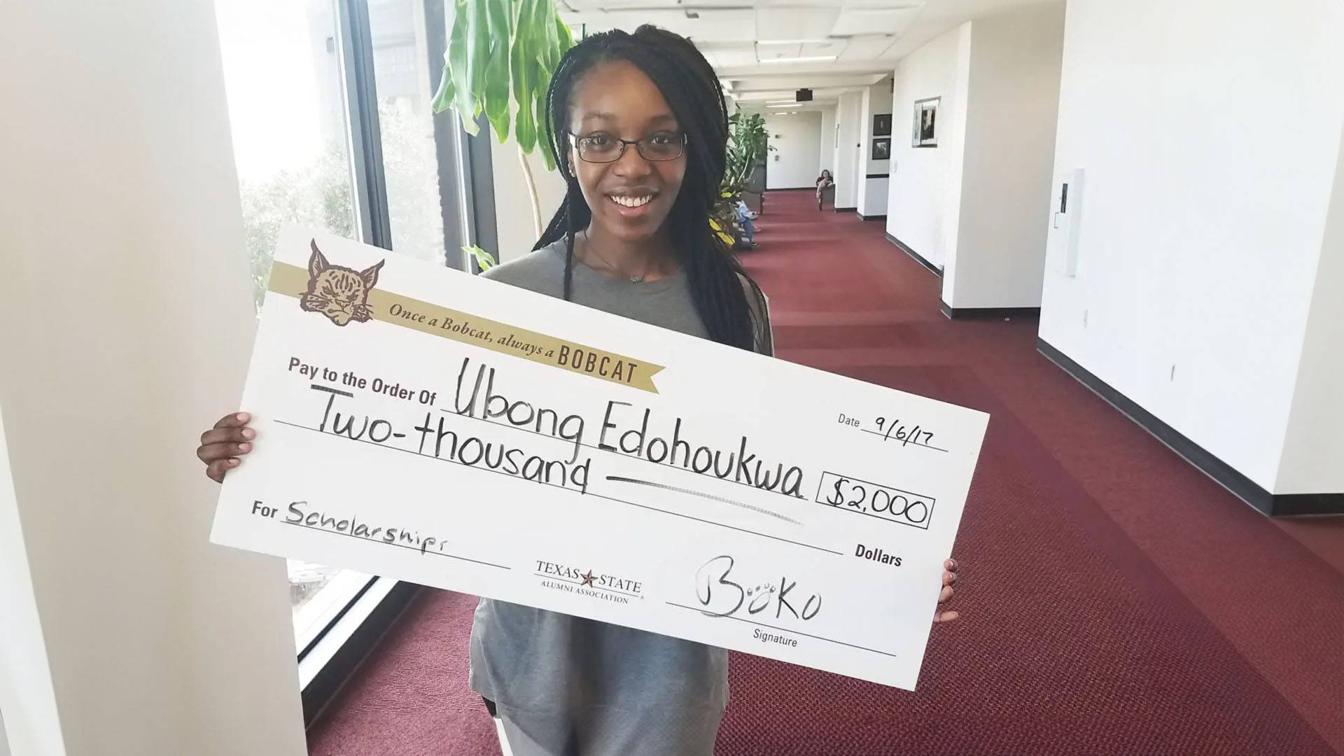 photo of woman holding check made out from Boko