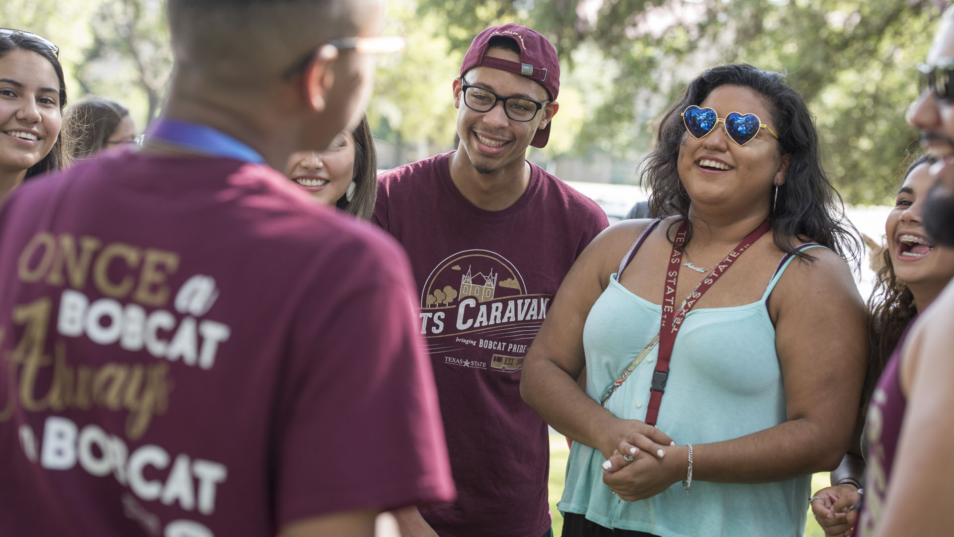 Photo of group wearing Texas State Shirts gathering around each other and smiling.