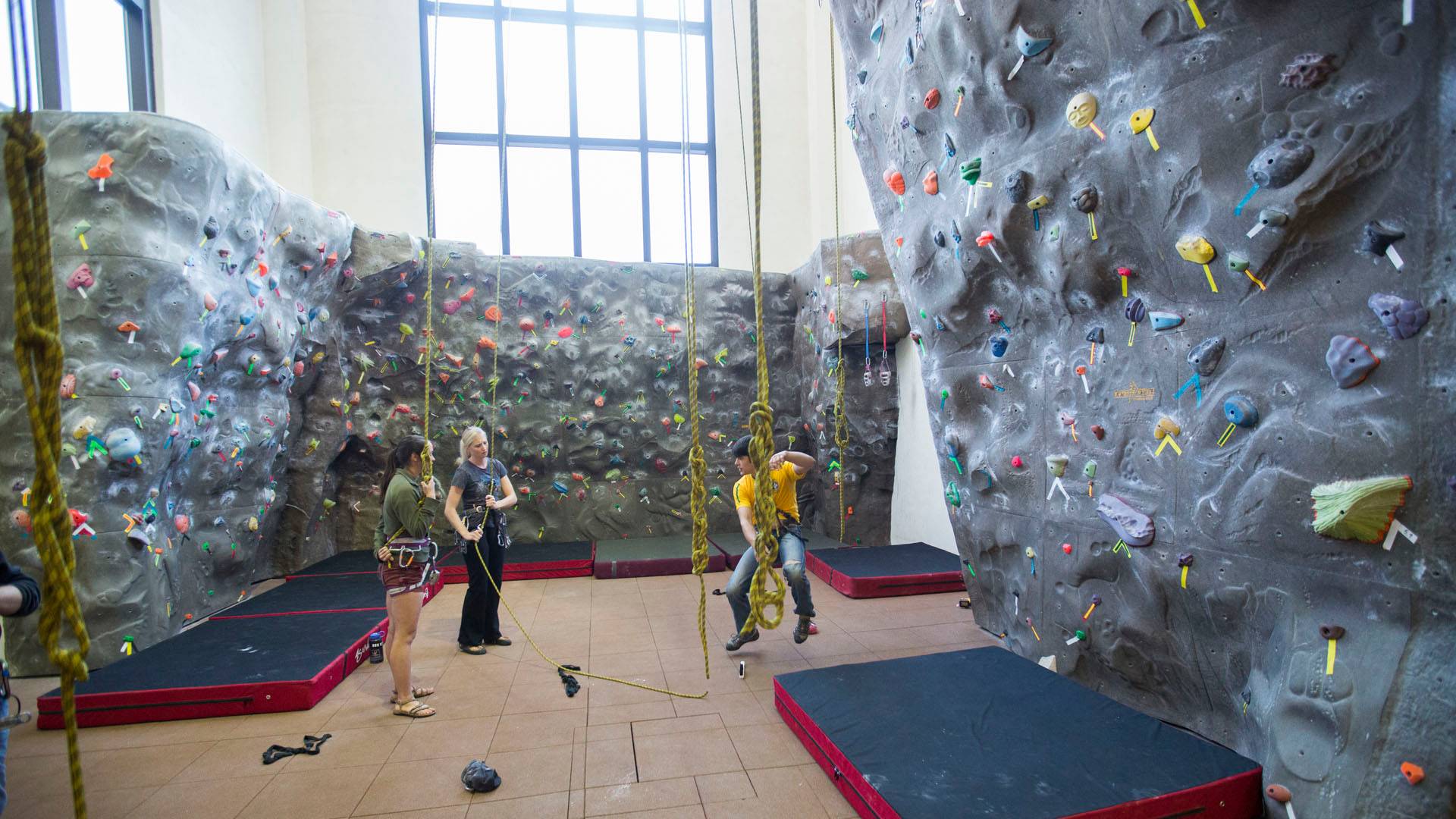 Group of three people using rock wall equipment in Texas State Rec Center.