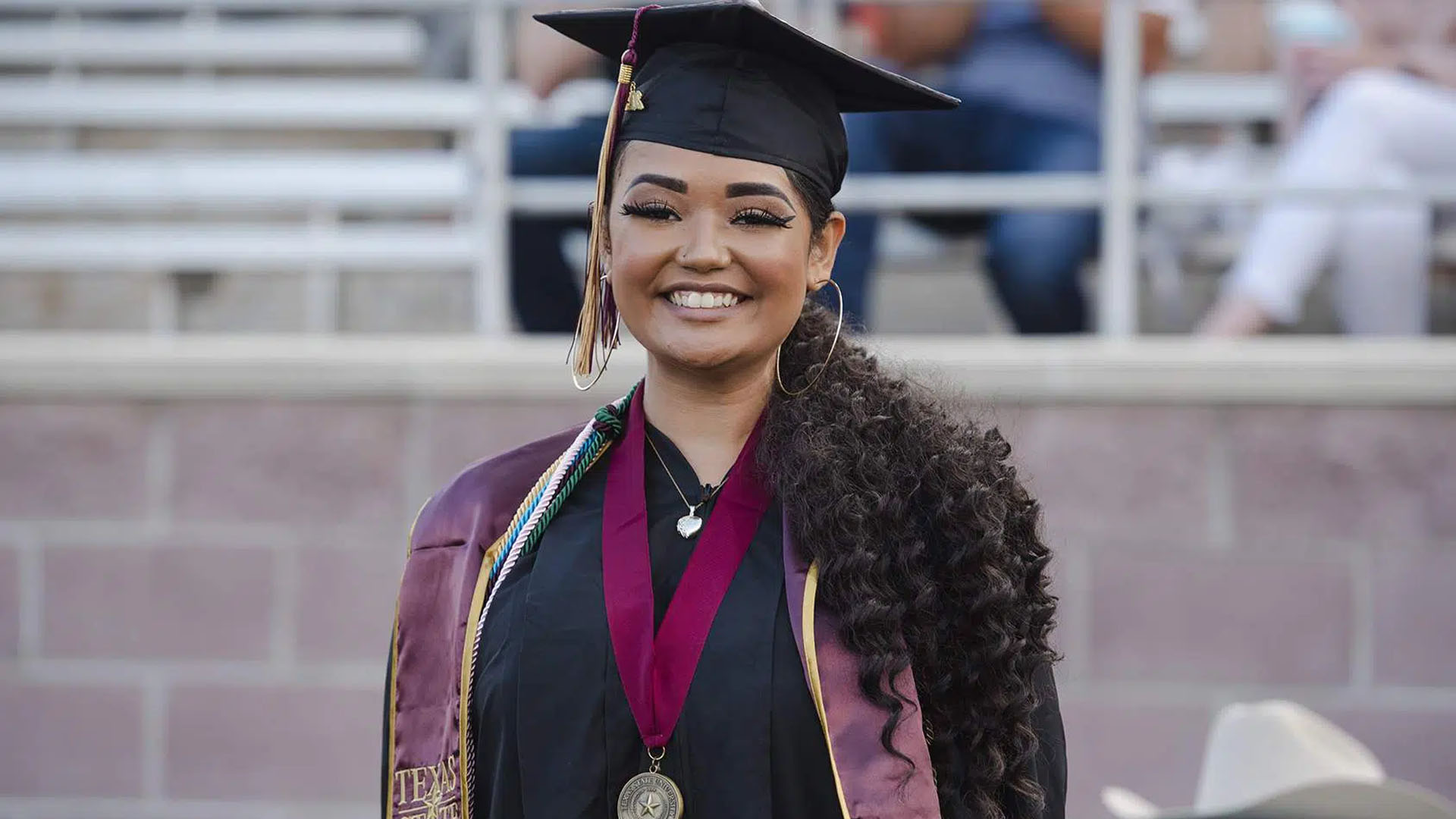 woman smiling while wearing graduation cap and gown