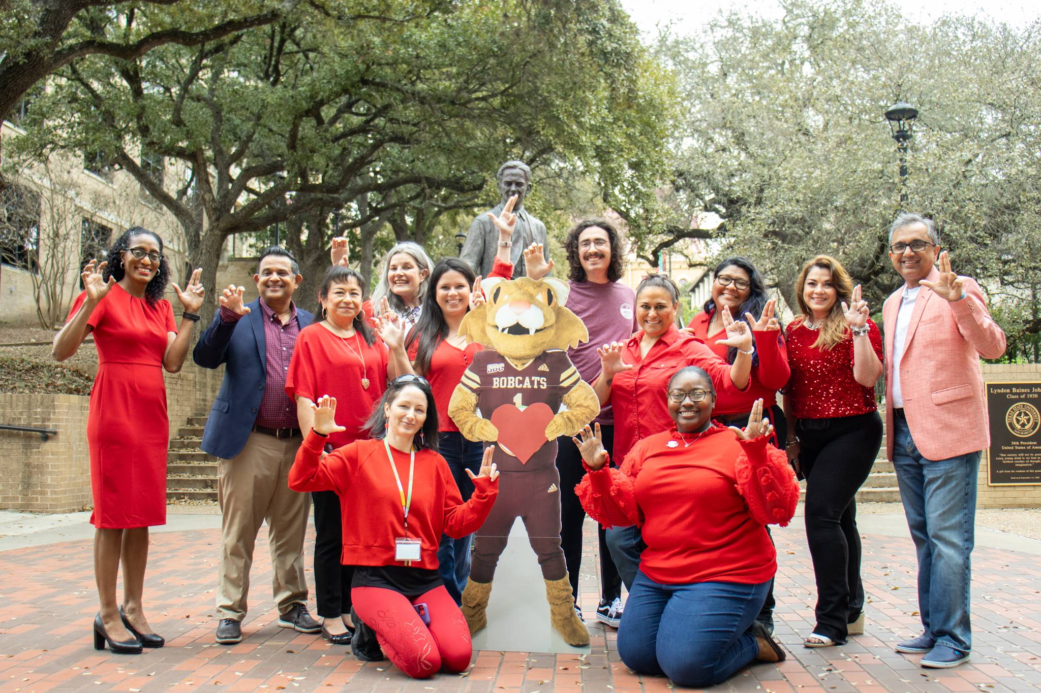 a group of employees wearing red in front of the LBJ statue