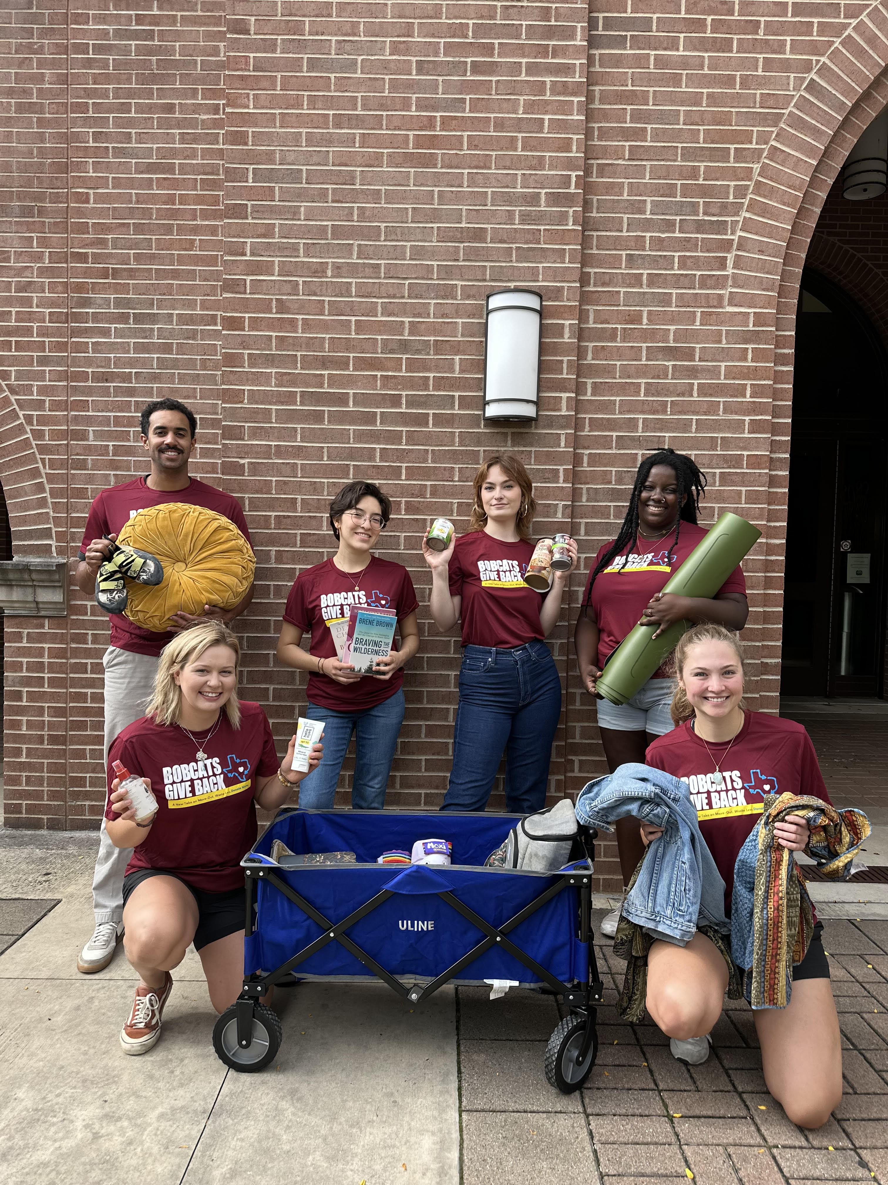 Bobcats Give Back staff pose with acceptable materials.