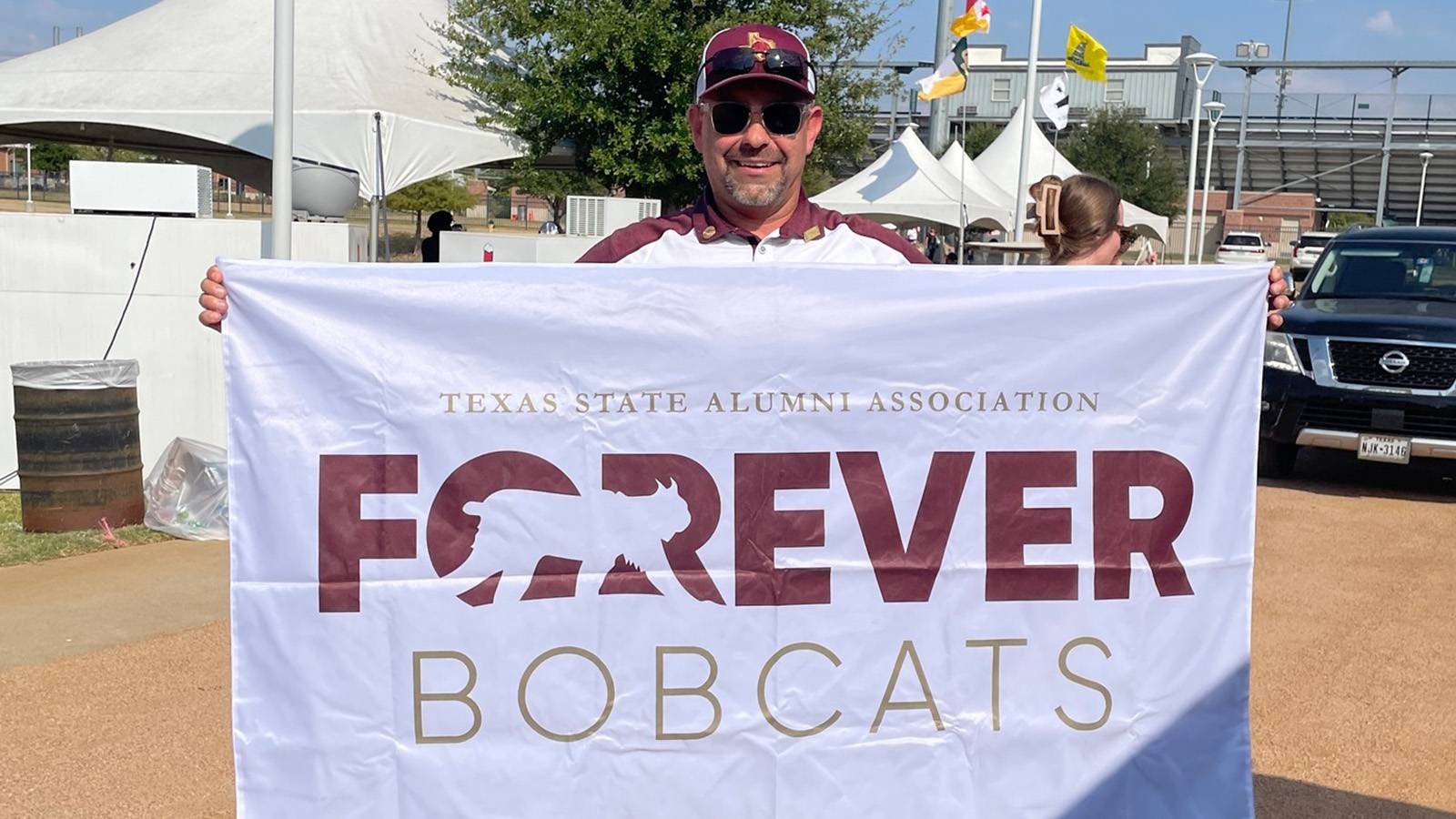 Man holding up forever bobcats flag