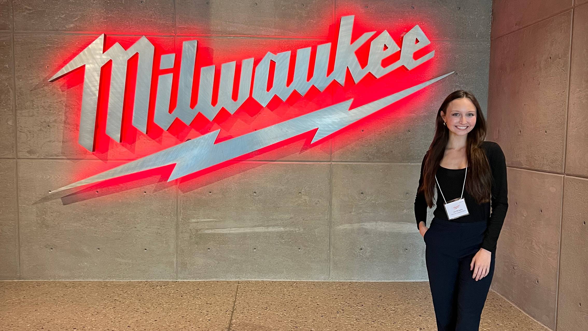 Joni McCawley poses for a photo next to the Milwuakee Tool sign.
