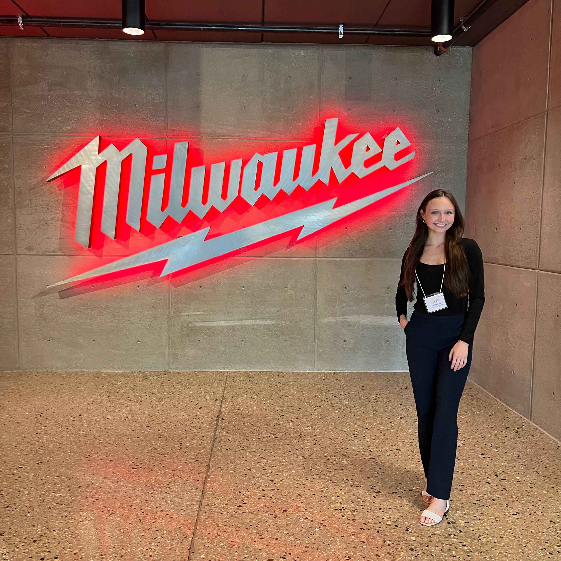 Joni McCawley poses for a photo next to the Milwaukee Tool sign.