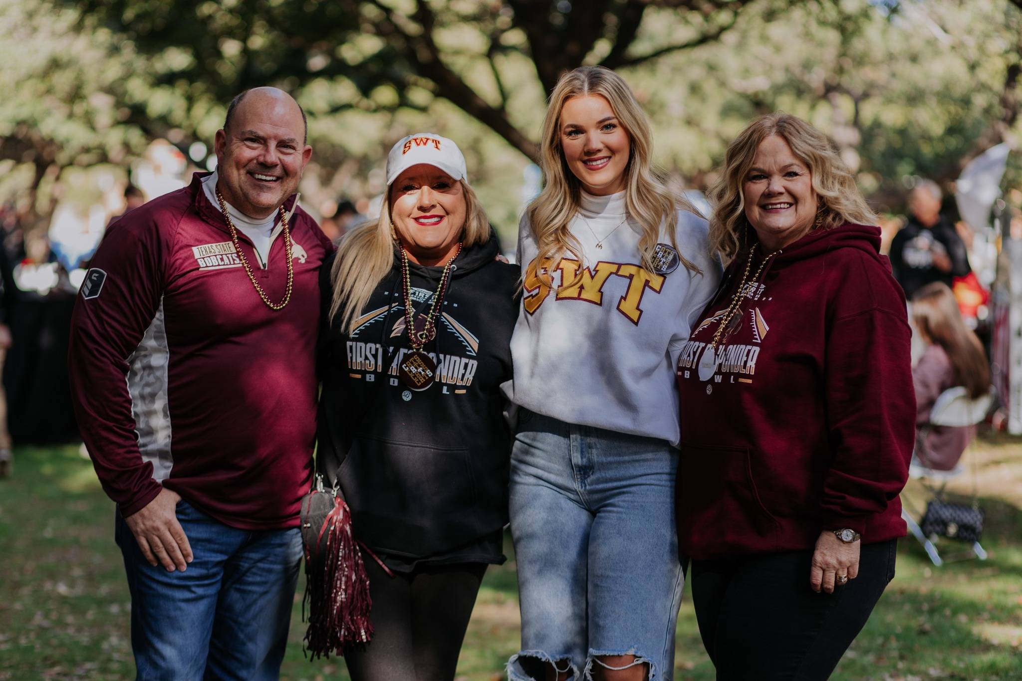 Group of four people wearing Texas State Merch at an Alumni Tailgate