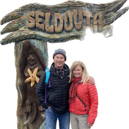 Photo of couple smiling in front of a "Seldouta" sign.