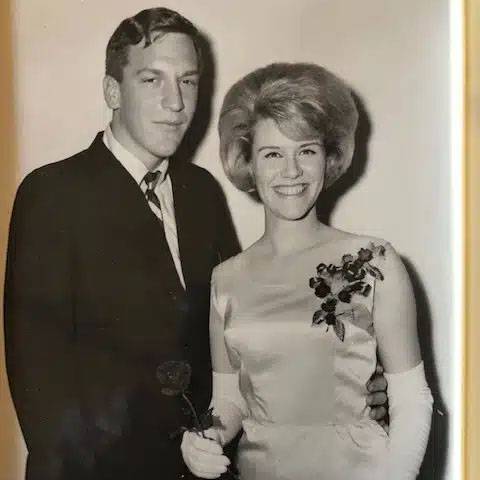 black and white photo of a couple at a wedding, woman is smiling and holding a rose