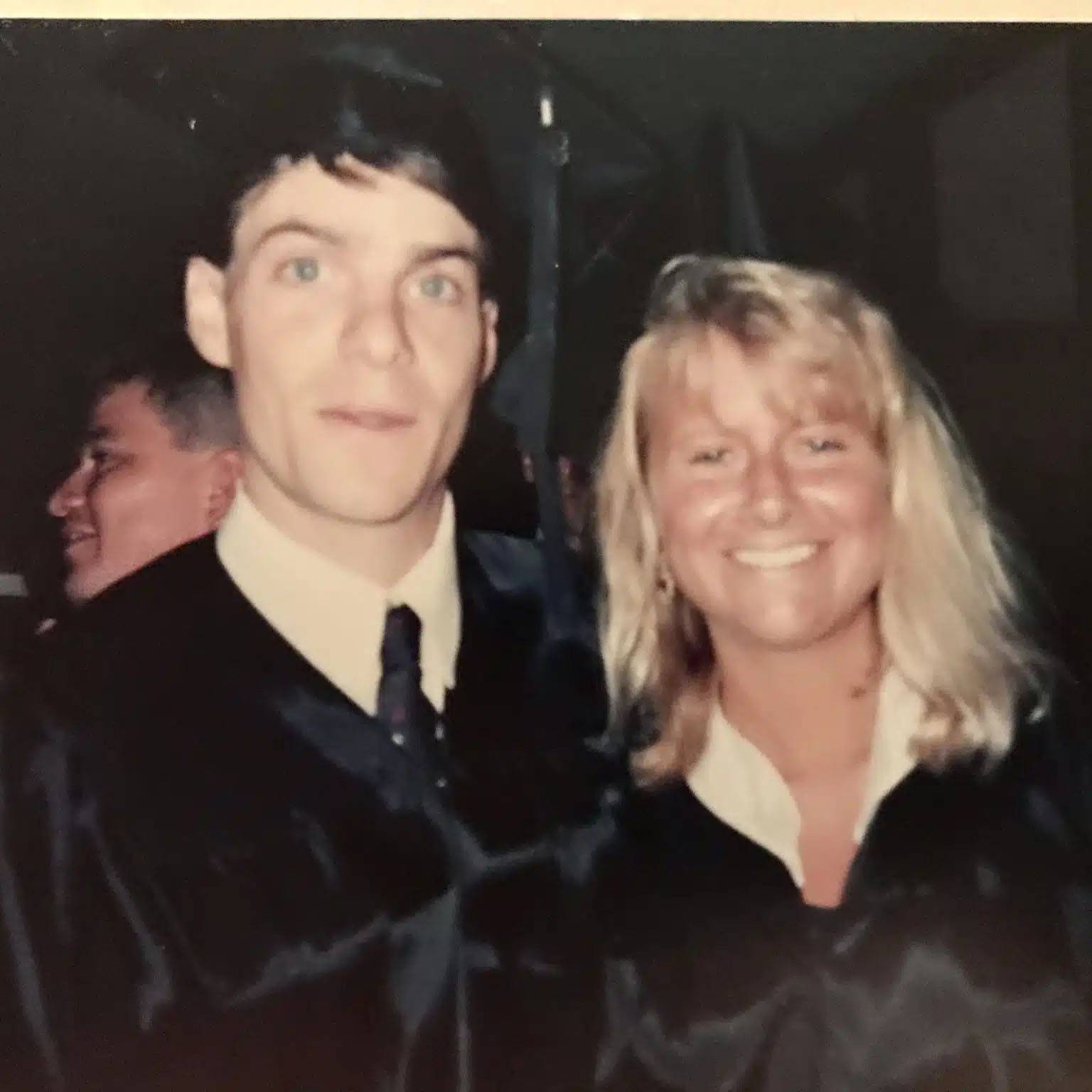 old photo of couple standing side by side smiling.