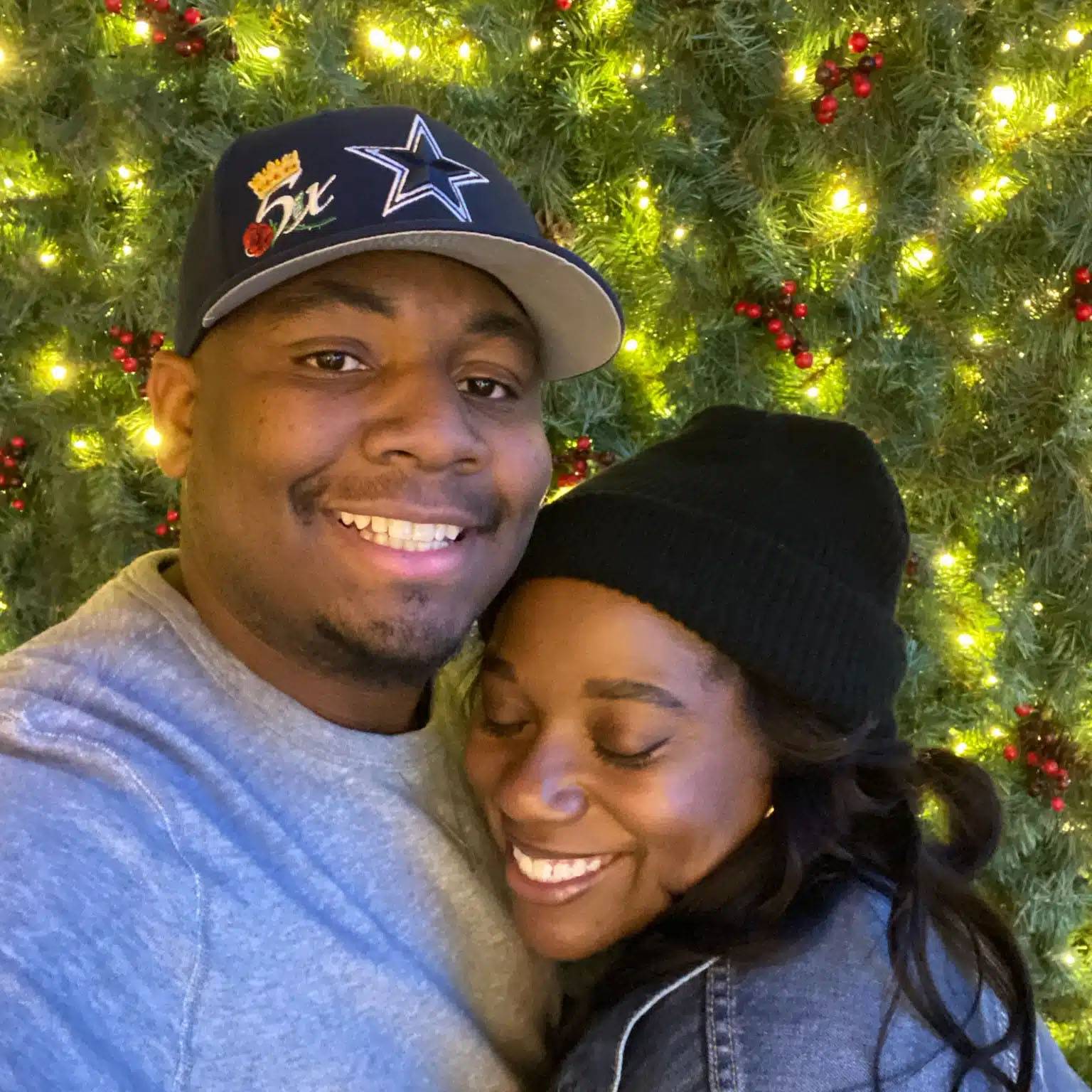 couple smiling in front of a Christmas tree