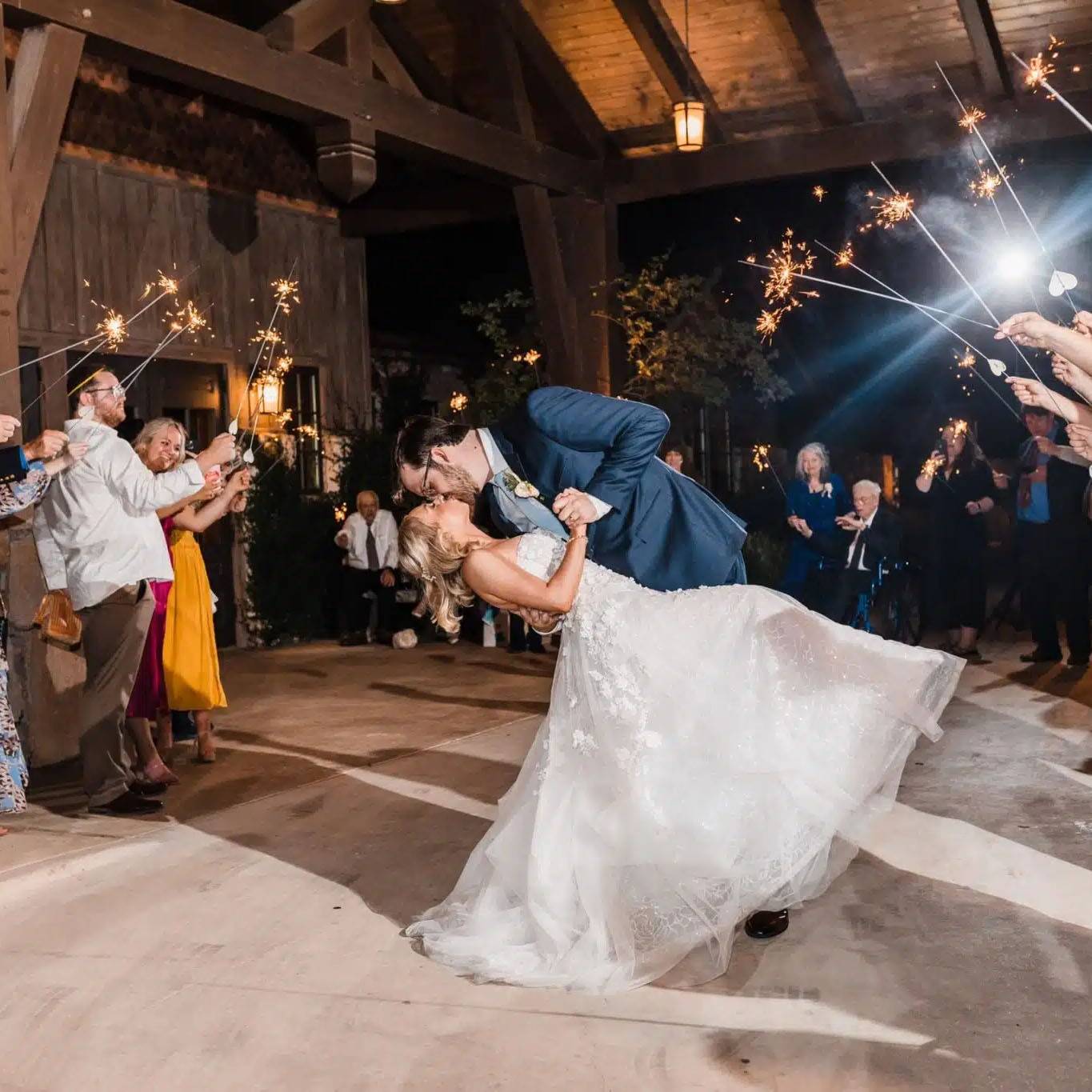 photo of couple in wedding attire kissing surrounded by sparklers