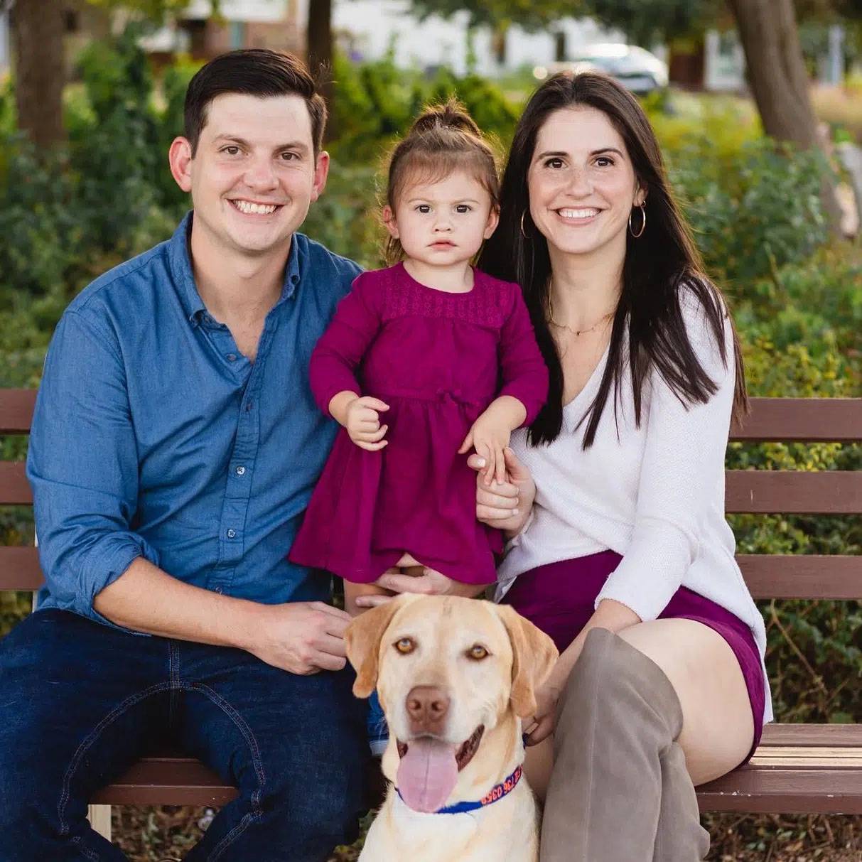 Photo of couple sitting with their baby and dog.