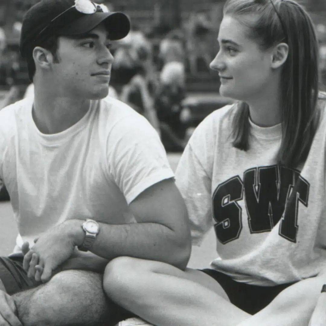 Photo of couple sitting down and looking at each other. Black and White photo. Wearing SWT shirts.