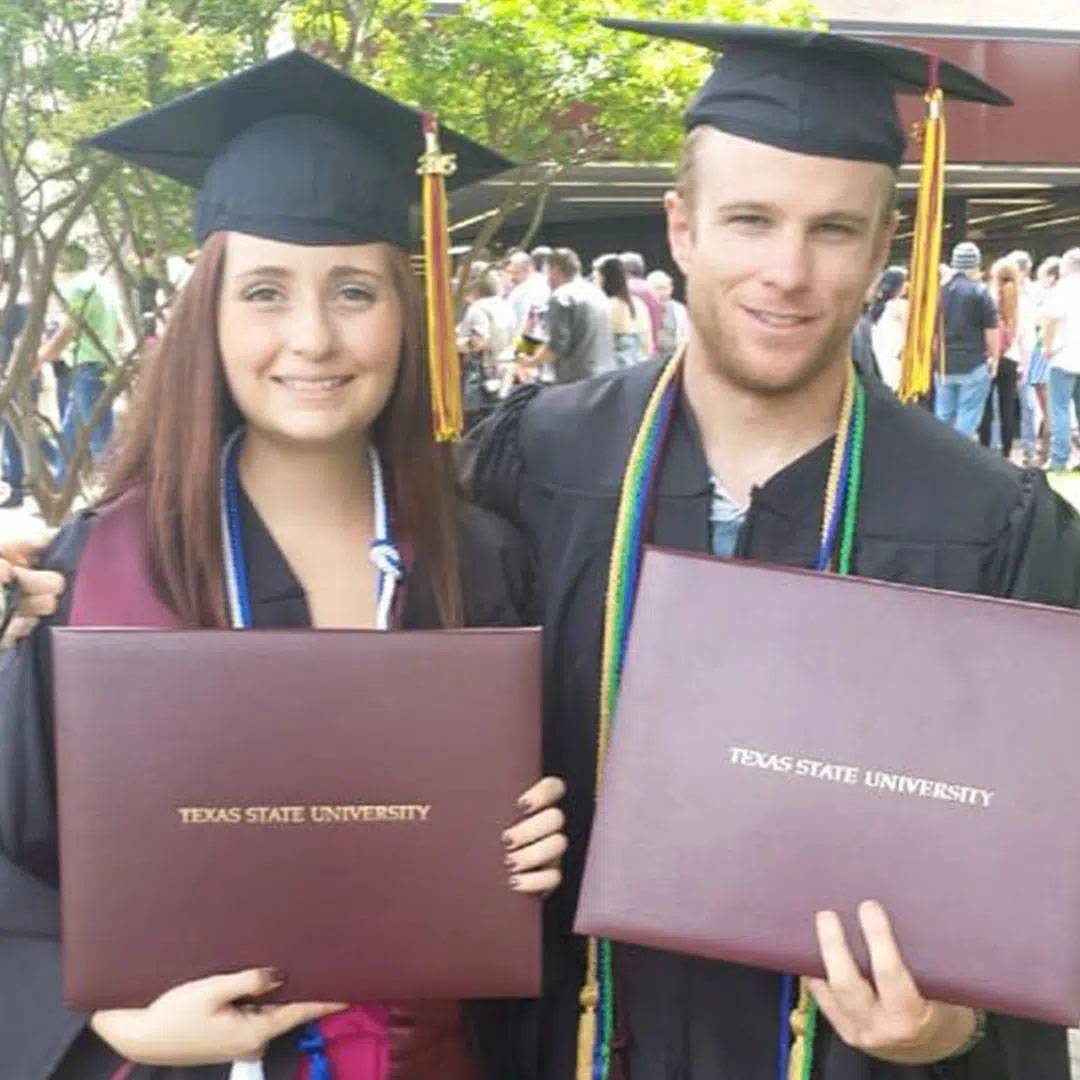 Photo of couple at graduation both holding diplomas and smiling