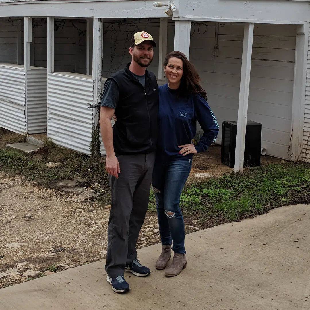 Photo of couple standing together next to a white building