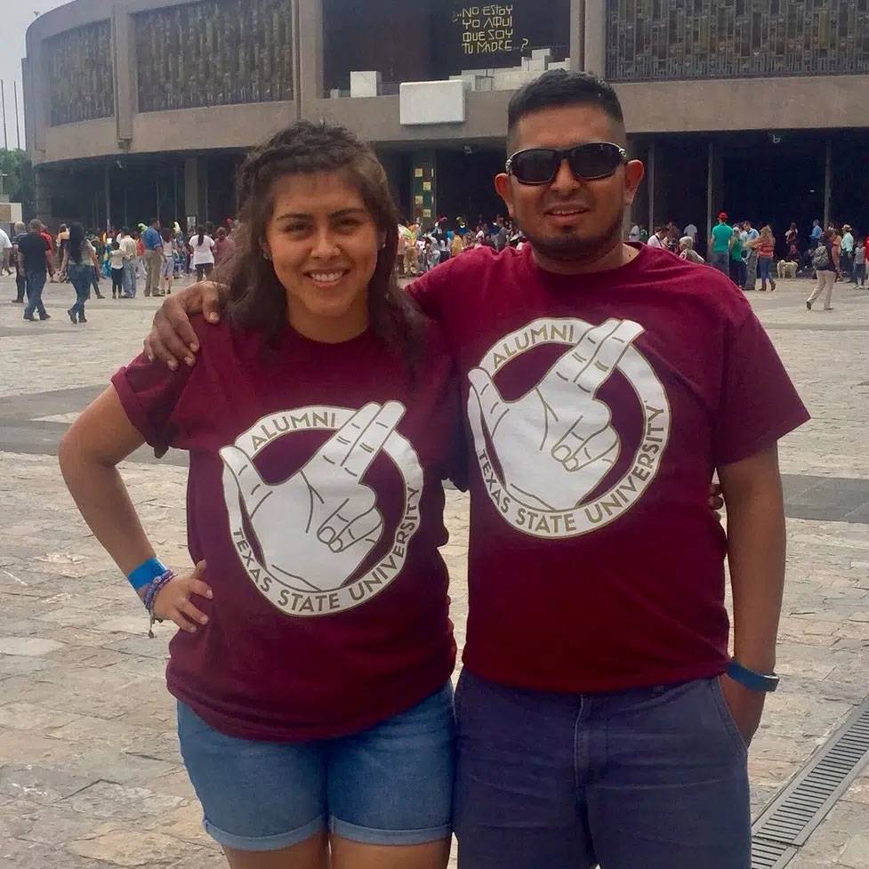 Photo of coupke standing together wearing TXST Alumni tshirts