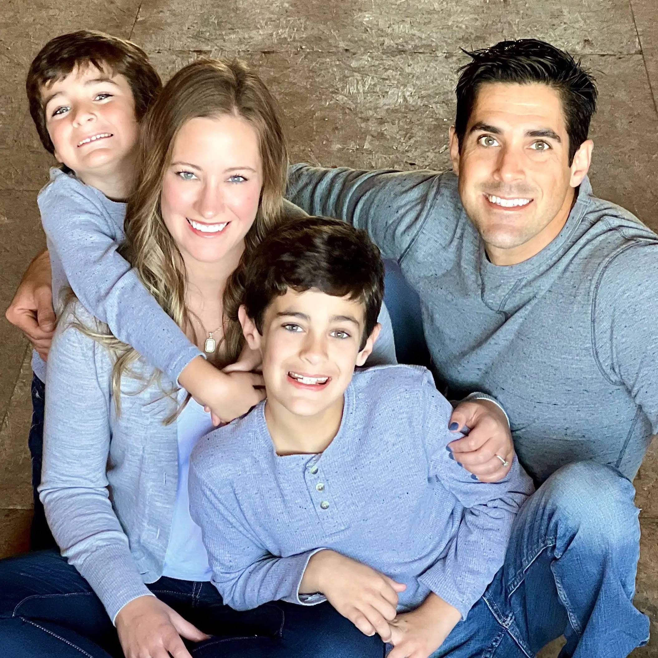 Family photo of the couple and their kids, sitting on concrete wearing blue