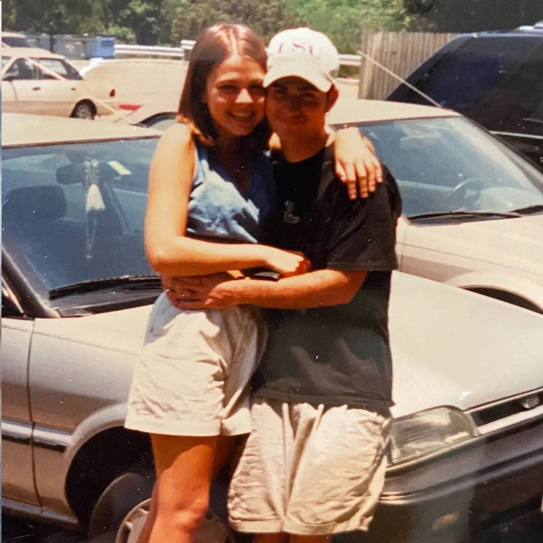 Photo of couple sitting together on car hood. Photo is vintage.