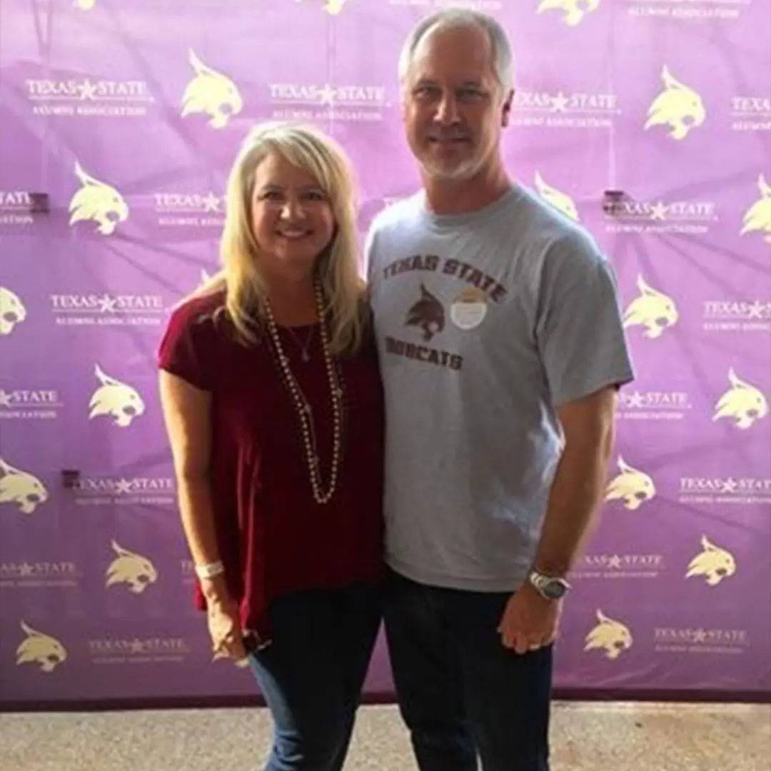 Photo of couple together at TXST alumni event, wearing TXST merch