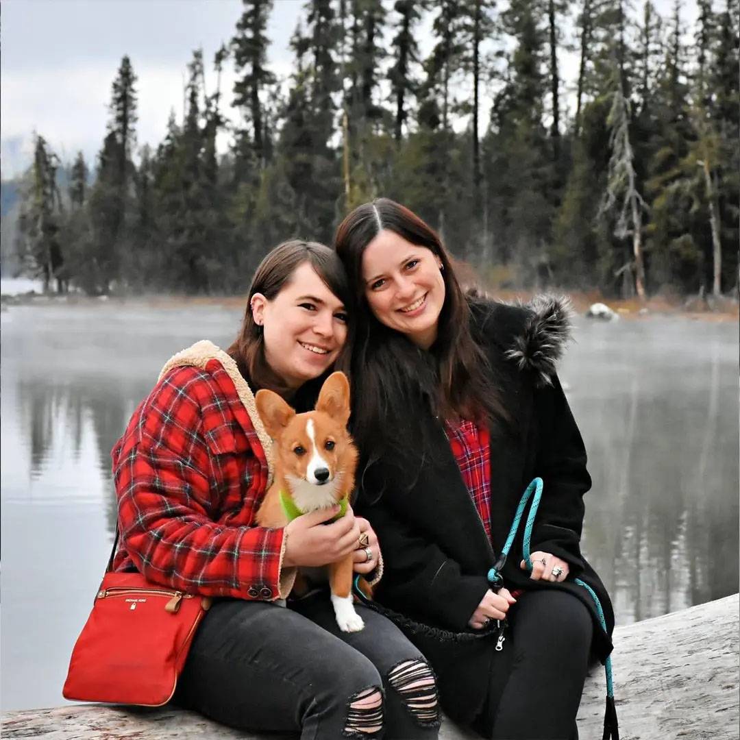 Photo of two women and their dog against a lake