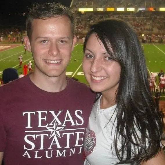 Photo of couple smiling and wearing TXST merch