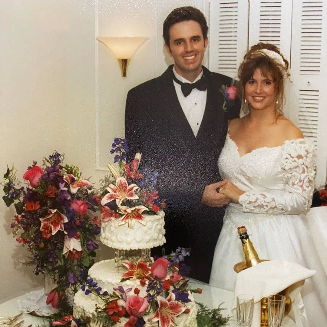 Photo of ocuple at wedding standing next to a spread of food