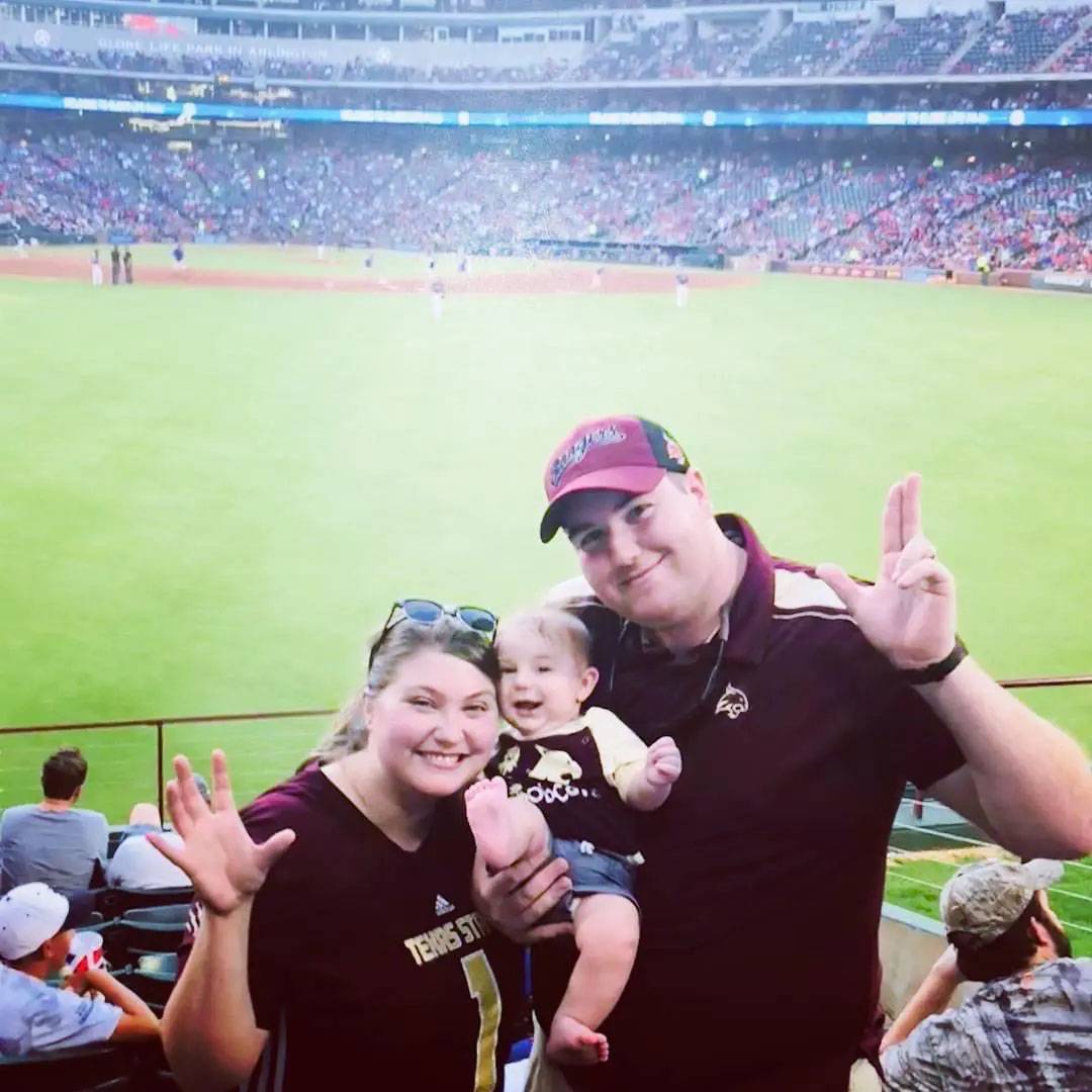 photo of couple and baby at baseball game