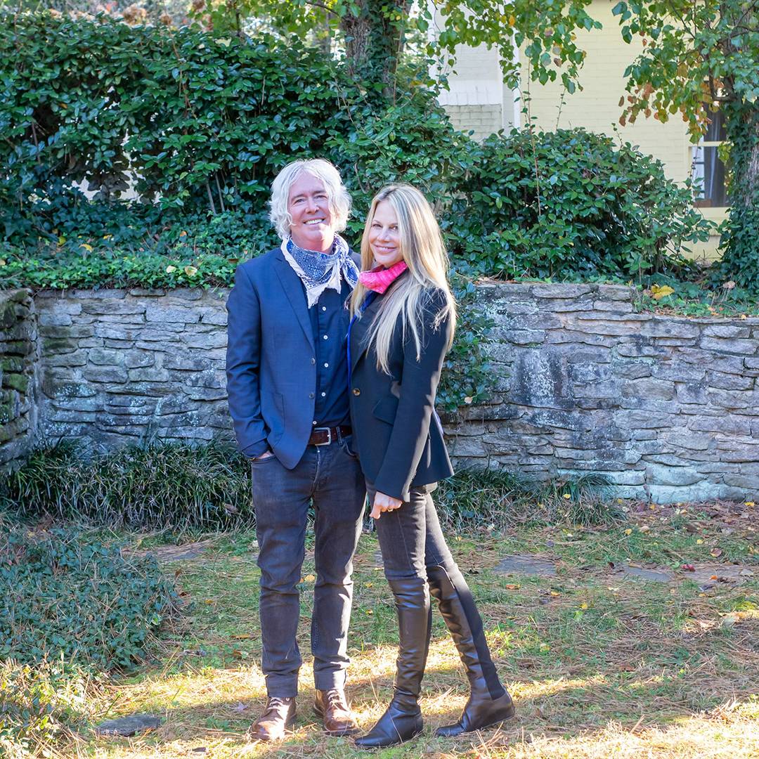 photo of couple standing in front of cobblestone wall