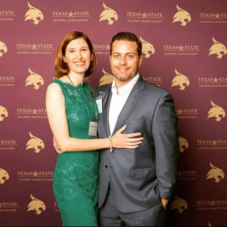 photo of couple smiling against TXST backdrop