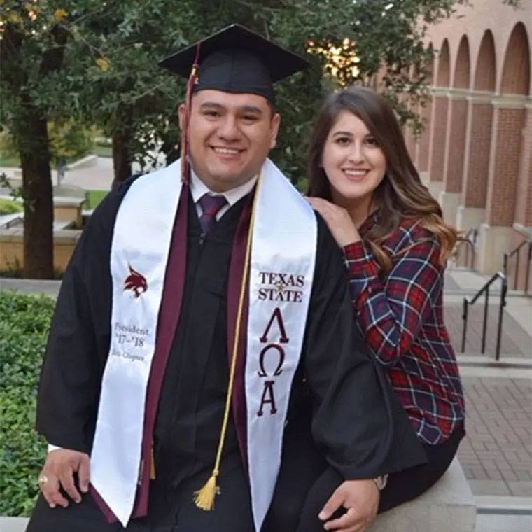 photo of couple in graduation clothes on campus