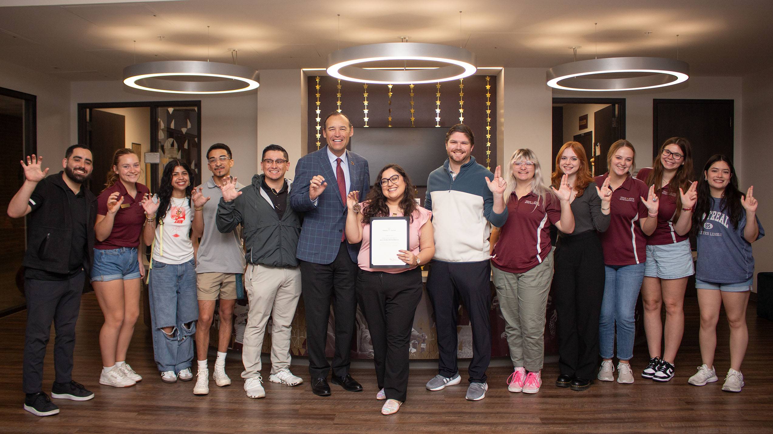 A group of TXST staff poses for a photo with President Kelly Damphousse and honoree Allison Menchaca (middle).