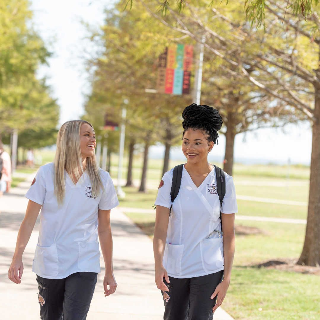 two female students in nursing scrubs walking on the round rock campus