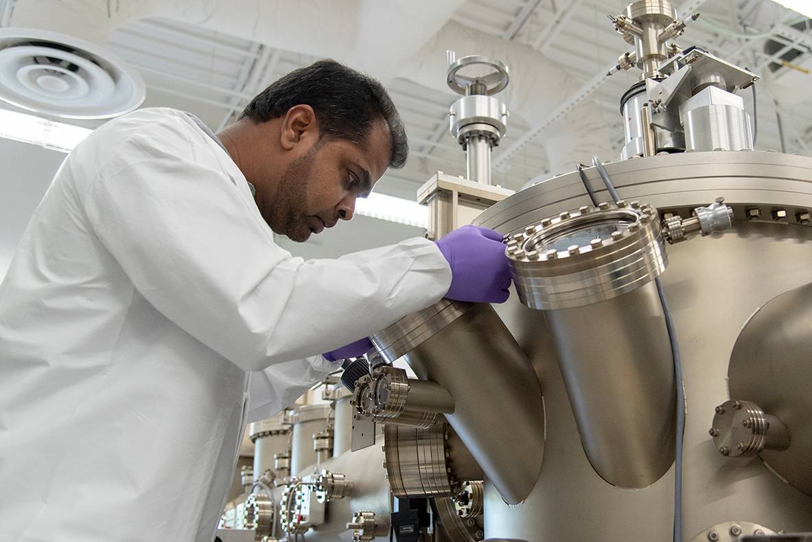 man in white lab coat looking at large scientific instrument