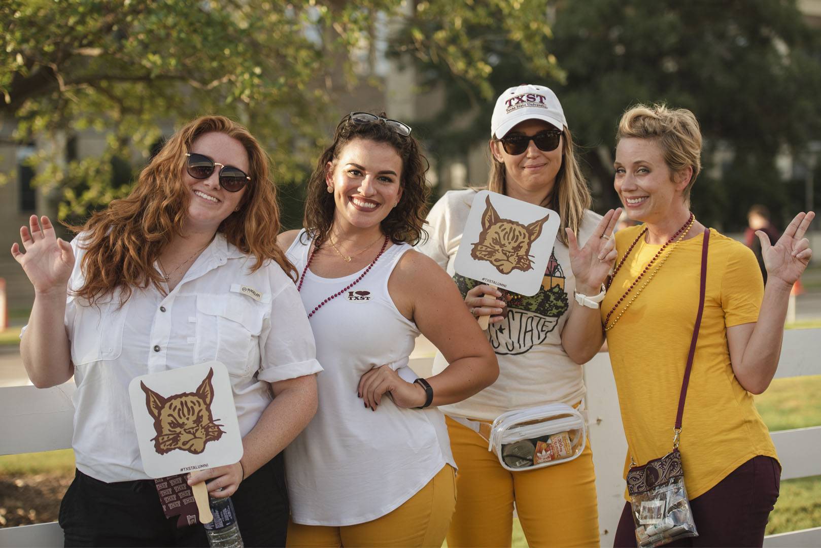 group of four women wearing TXST gear at alumni event