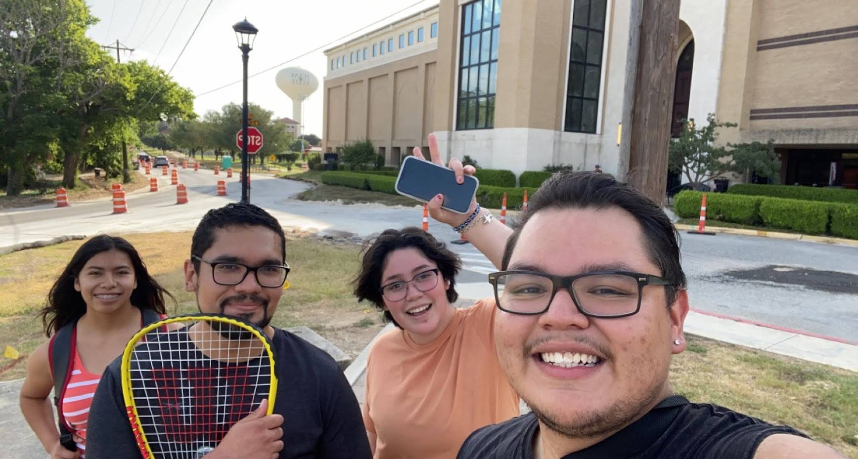 four students in front of Rec Center after a game of doubles tennis