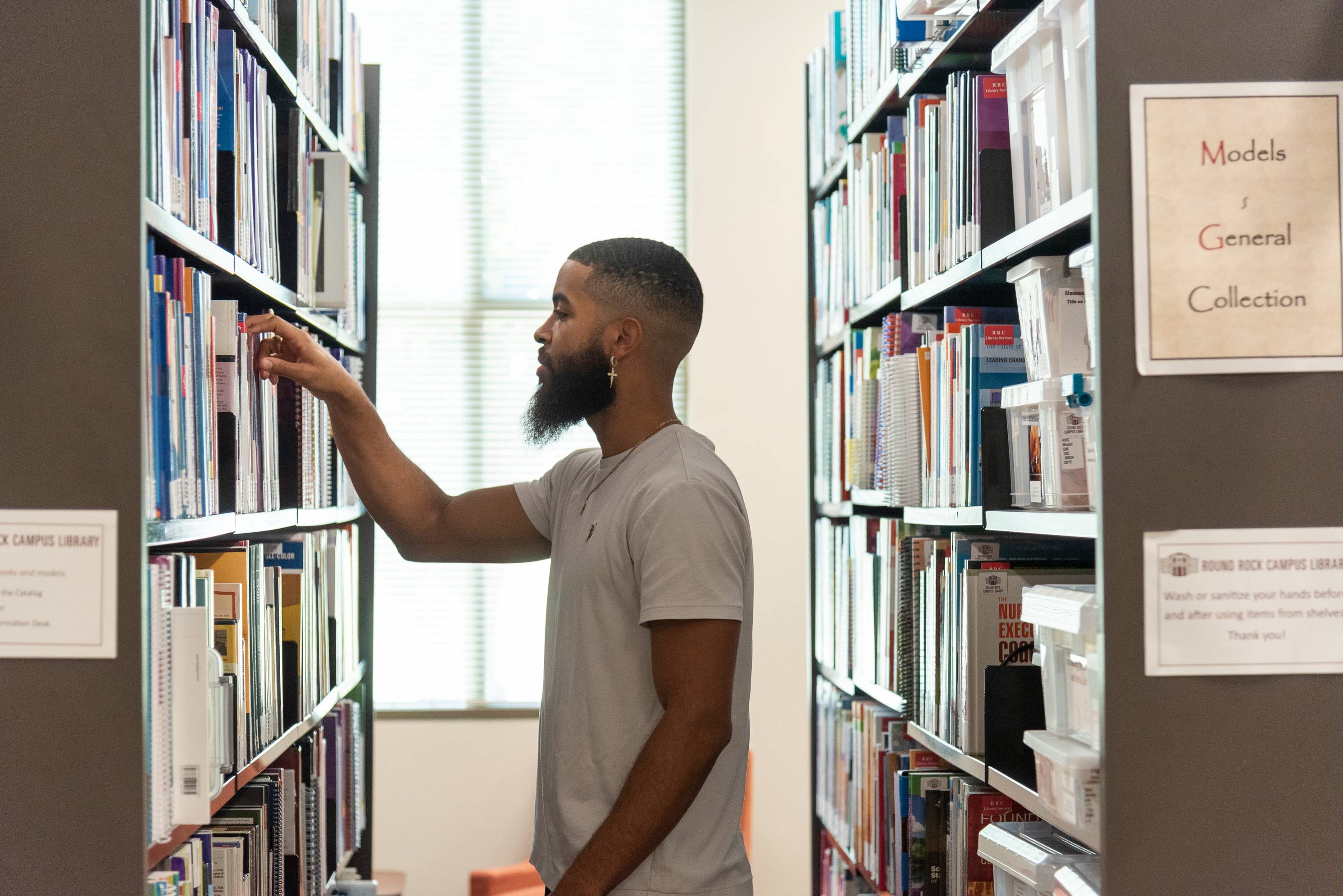 A guy looking at books in the library