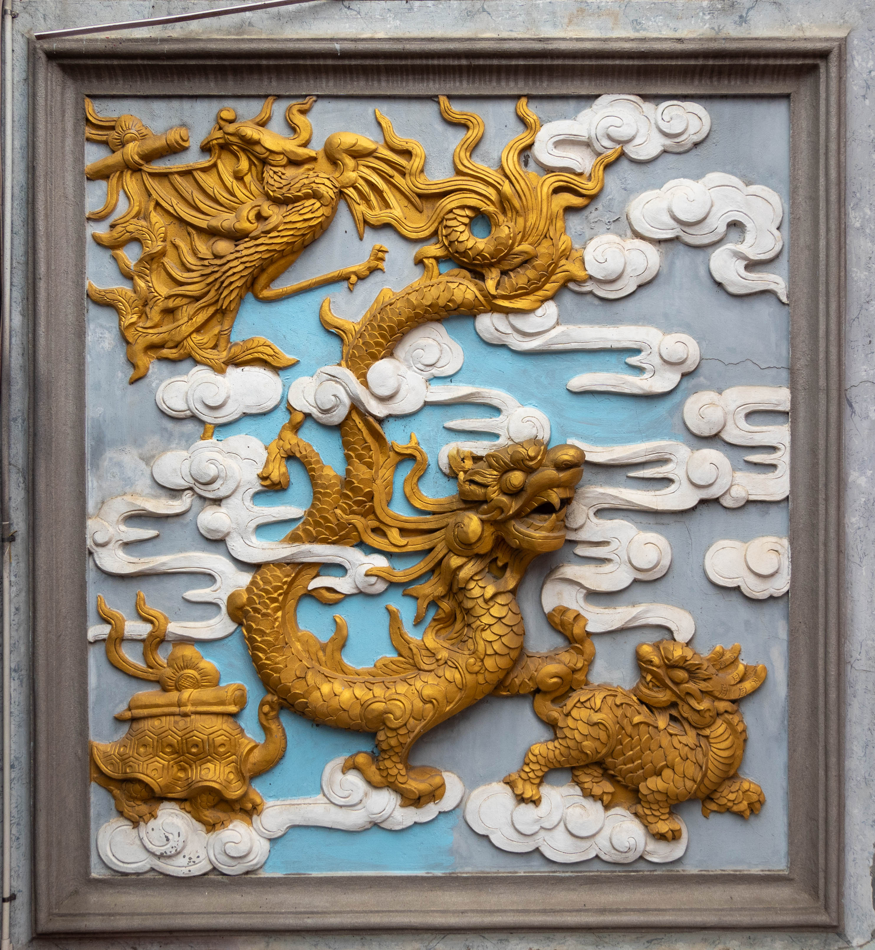 plaque showing dragon in center tortoise in lower left, unicorn in lower right, and phoenix in upper left