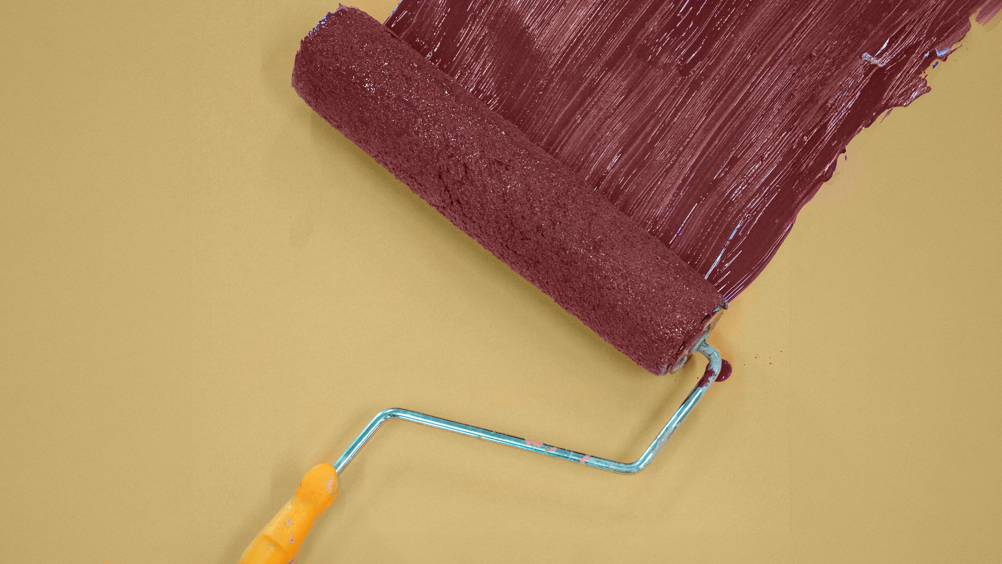 paint roller applying TXST maroon to a TXST gold background