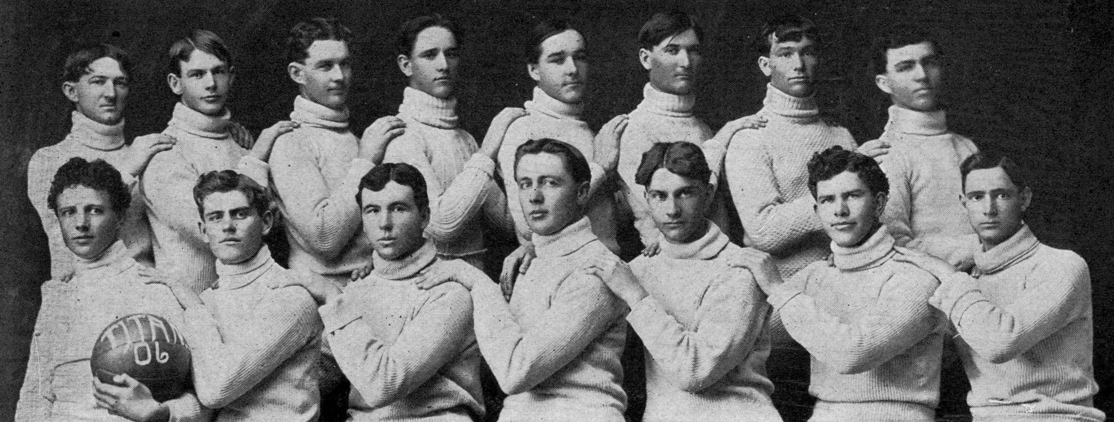 Aged black and white photo of the men's basketball team from 1906. Posing in two rows, the players wear matching turtlenecks, and a man in the bottom row, second from the left holds up a basketball labeled 'Titans '06'.