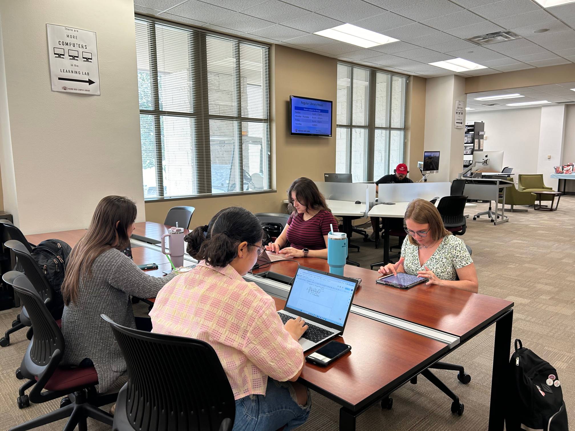 A room with people working on laptops at a table