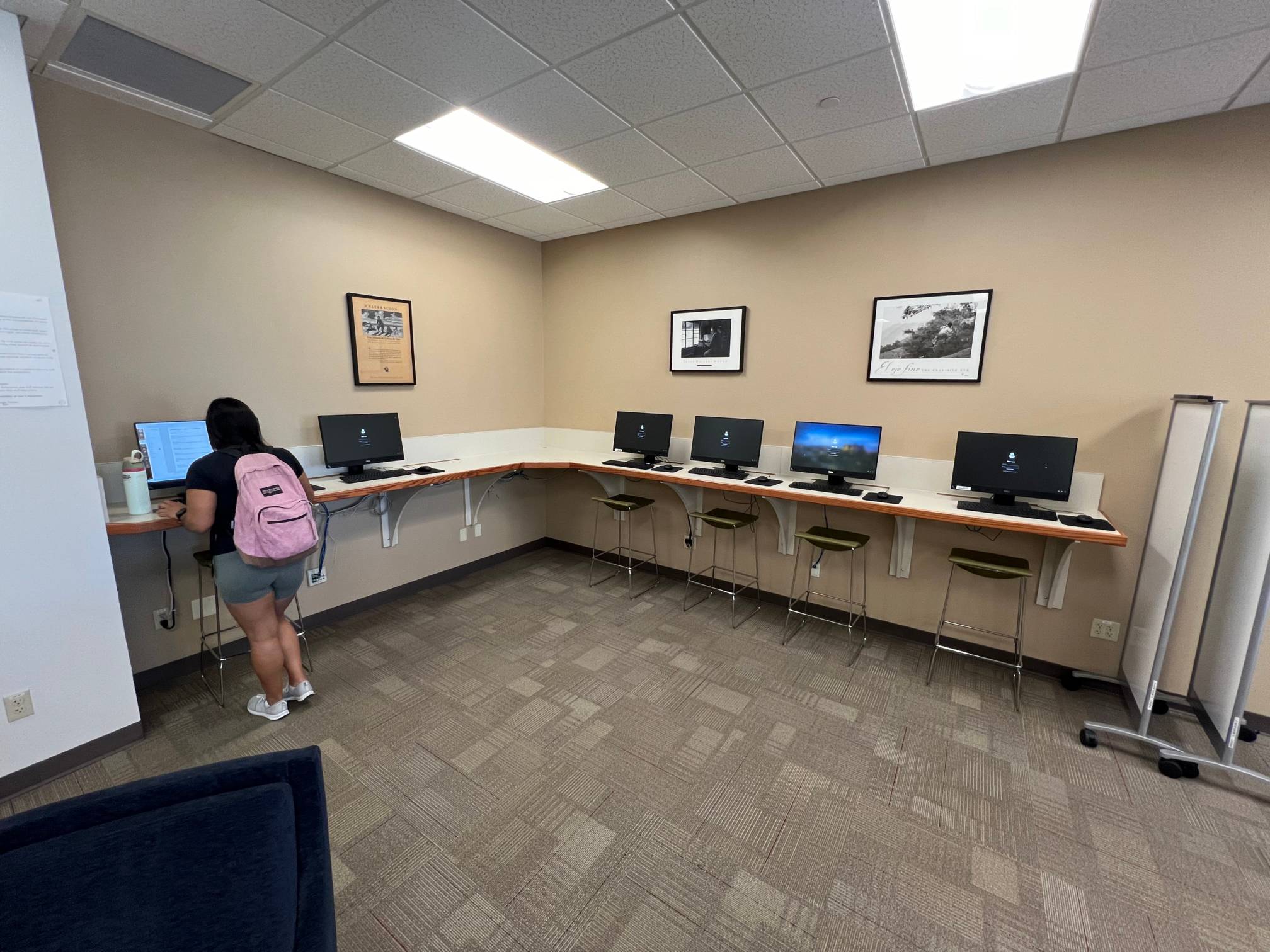 A person using a computer with additional computers on a long counter.