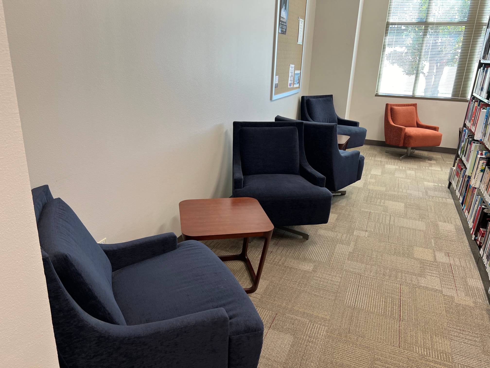 Multiple lounge chairs, a small table, and a bookshelf.