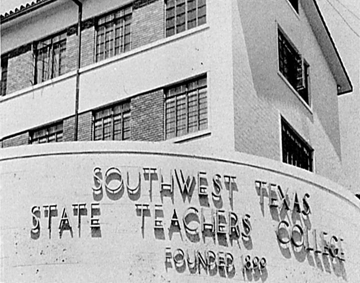 Aged photograph of a large, arced concrete sign in front of the corner of a brick building. Raised letters read 'Southwest Texas State Teachers College. Founded 1899.'