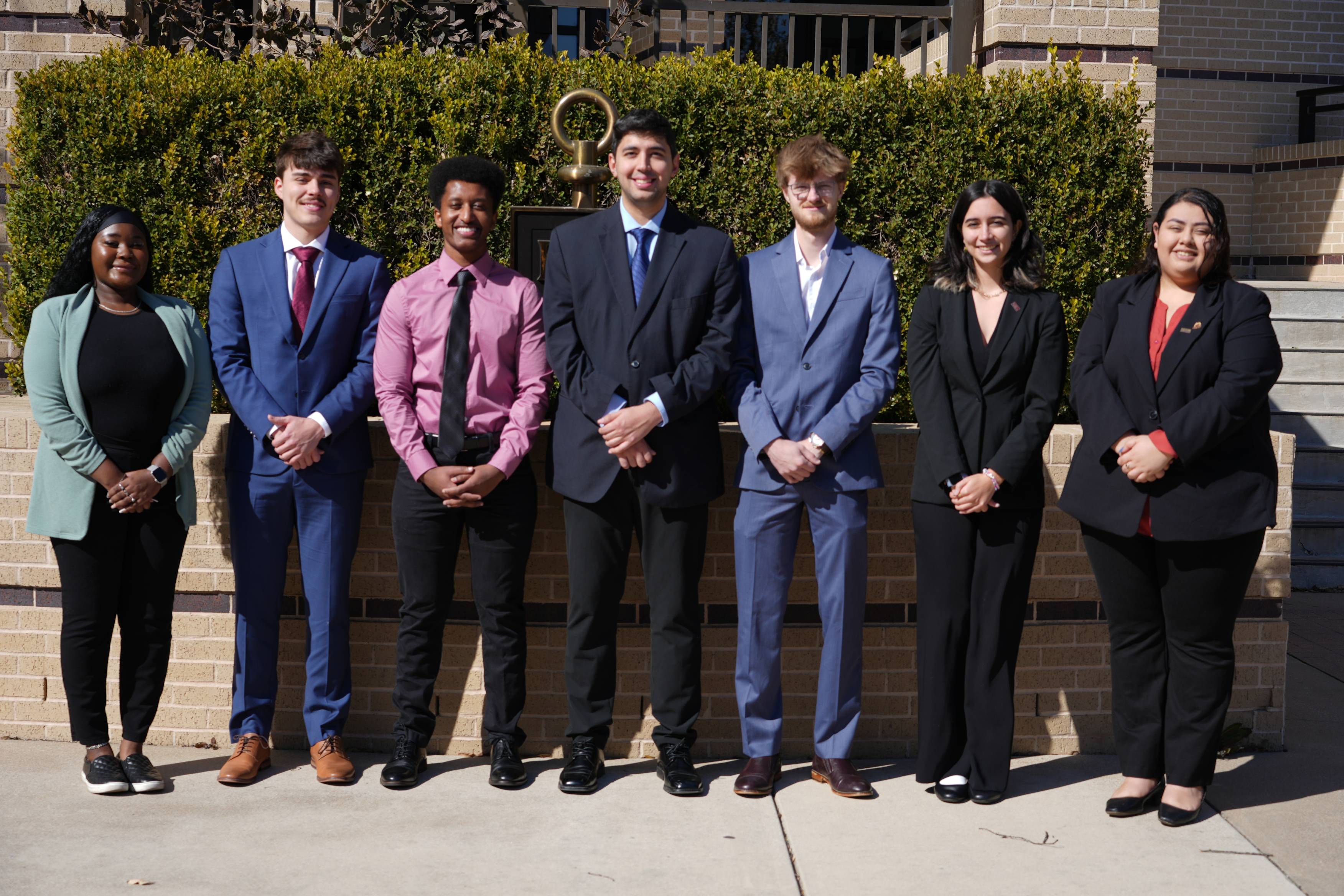 Student Business Council members standing in front of the Beta Gamma Sigma symbol outside of McCoy College of Business