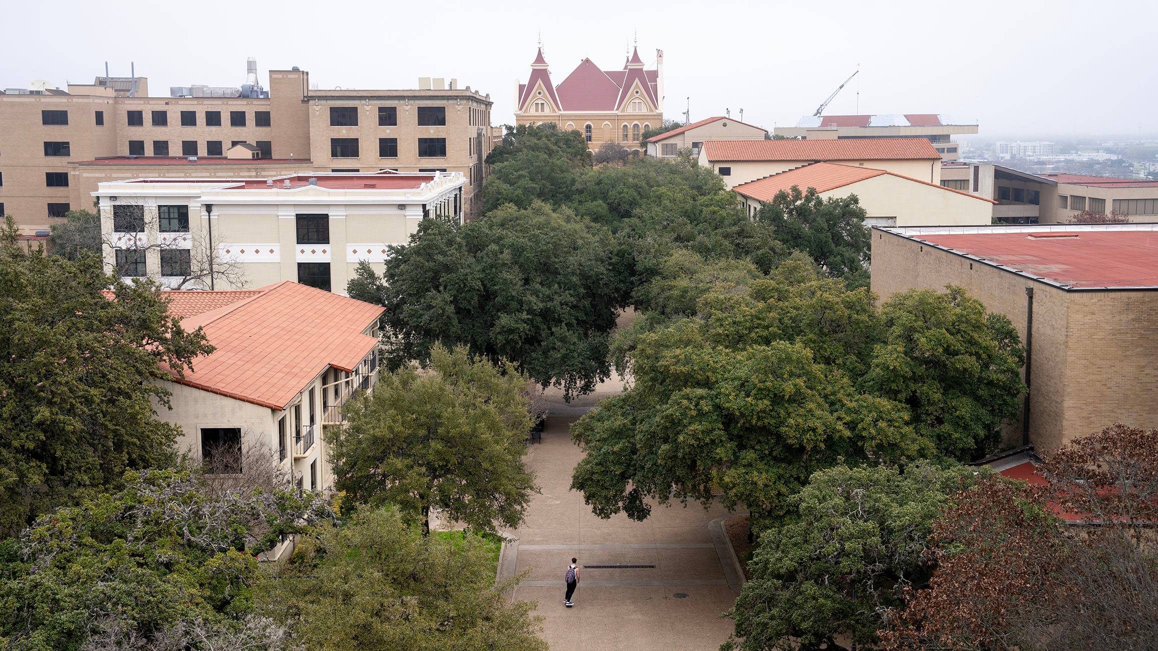 Aerial view of campus with trees and buildings, foggy day.